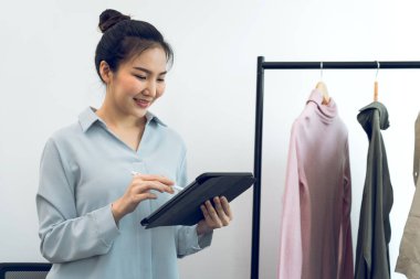 Genç Asyalı girişimciler online satın alma siparişlerini kontrol ederken bir tablet kullanıyorlar.