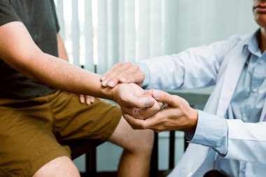 Fizyoterapist, klinikte bilek kemiğine bastırarak hastanın bileğini kontrol ediyor..