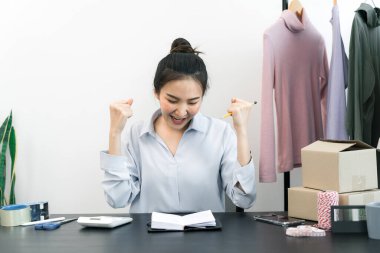 Genç Asyalı girişimciler giysilerini hedefe satarken neşeli davranıyorlar..