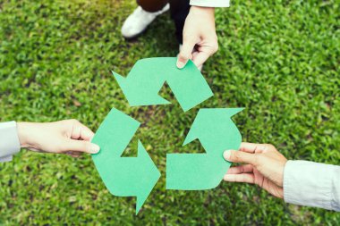 Yeşil arka planda geri dönüşüm sembolü tutan insanlar. Dünya Günü tatili kavramı.