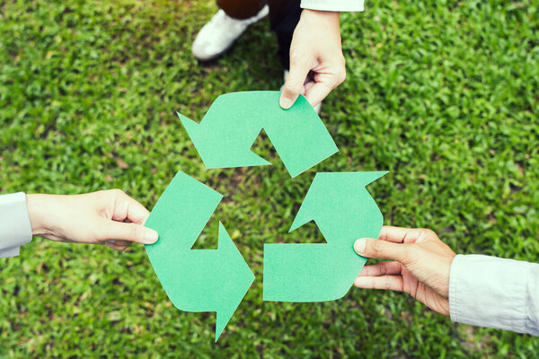People holding recycle symbol against green spring background. Earth day holiday concept.