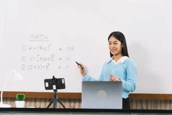 Teacher explaining the numbers on the board while video calling with students studying online.