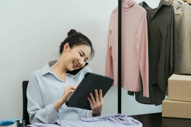 Bir tabletin envanterini kontrol ederken Asyalı girişimci bir müşteriyle telefonda konuşuyor..