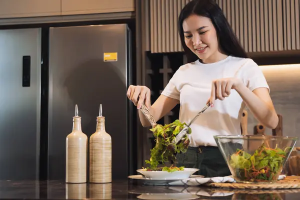 家庭のキッチンカウンターでサラダを作るために新鮮な野菜を準備するアジアの主婦 ロイヤリティフリーのストック画像