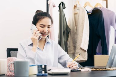 Asyalı girişimci telefonda müşterilerle kamyonetleri hakkında konuşuyor..