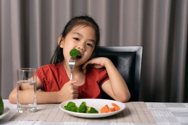 Asyalı küçük kız sağlıklı sebzeleri zevkle yiyor..