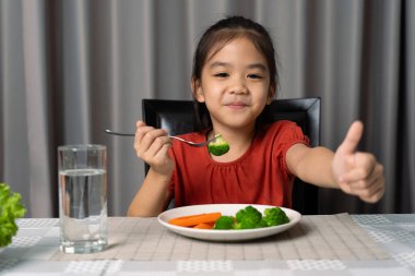 Sağlıklı sebze yediğini gösteren sevimli küçük bir kız..