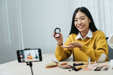 Genç Asyalı güzellik blogcusu kozmetik ürünlerin yanı sıra sosyal medya ağlarında makyaj derslerinin nasıl uygulanacağı ve kaydedileceği hakkında dersler sunuyor.