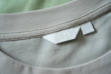 Gömlek kumaşı arka planındaki boş beyaz giysi bakım etiketini kapat.