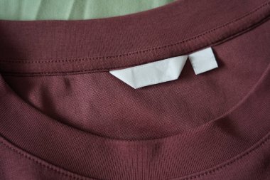 Gömlek kumaşı arka planındaki boş beyaz giysi bakım etiketini kapat.