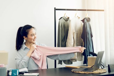 Genç Asyalı girişimciler, müşterilerin internetten izlemesi için oranlarını karşılaştırmak üzere gömlek seçiyorlar..