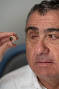 Göz uzmanımız göz protezi tutuyor ve bir hastayı göz hekimliği kliniğinde uygun bir işleme hazırlıyor.