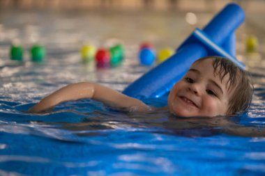 Mutlu çocuk mavi yüzme cihazıyla yüzme dersleri alıyor, su güvenliğini ve erken çocukluk gelişimini destekliyor.