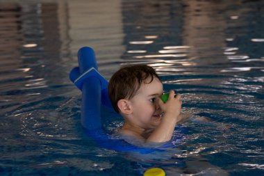 Küçük çocuk yüzme dersleri almaktan, yüzen oyuncaklarla oynamaktan ve kapalı havuzda şişme kolluk takmaktan hoşlanıyor.