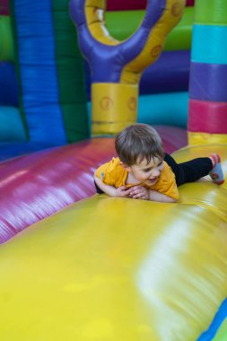 Renkli şişme bir şatoda emekleyen mutlu bir çocuk lunaparkta ya da doğum günü partisinde eğleniyor.