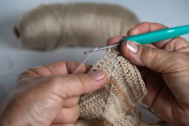 El işi kancayı ustalıkla kullanmak, iplikle karışık desenler yaratmak, el yapımı tekstil sanatını sergilemek.