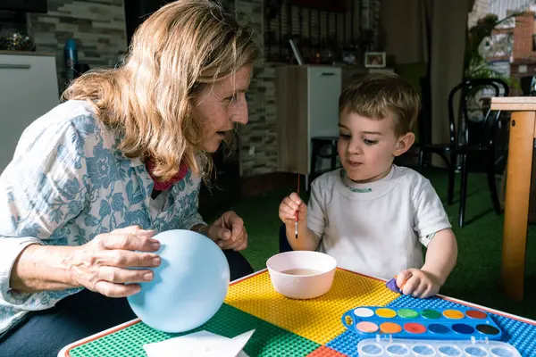 Büyükanne ve torun birlikte yaratıcı zaman geçirmeyi, suluboya bir balonda resim yapmayı, aile bağlarını ve sanatsal ifadeyi teşvik etmeyi seviyorlar.