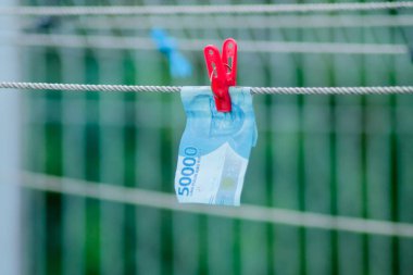 Para aklama konsepti. Rupiah faturaları çamaşır ipine asılı. Para aklamanın sembolü. Uzayın yumuşak odaklanmasını kopyala Para çamaşır ipinde.