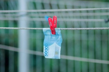 Para aklama konsepti. Rupiah faturaları çamaşır ipine asılı. Para aklamanın sembolü. Uzayın yumuşak odaklanmasını kopyala Para çamaşır ipinde.