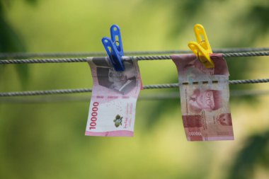 Para aklama konsepti. Rupiah faturaları çamaşır ipine asılı. Para aklamanın sembolü. Uzayın yumuşak odaklanmasını kopyala Para çamaşır ipinde.
