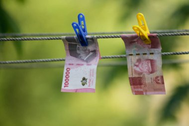 Para aklama konsepti. Rupiah faturaları çamaşır ipine asılı. Para aklamanın sembolü. Uzayın yumuşak odaklanmasını kopyala Para çamaşır ipinde.