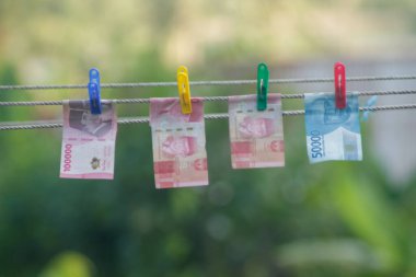 Para aklama konsepti. Rupiah faturaları çamaşır ipine asılı. Para aklamanın sembolü. Uzayın yumuşak odaklanmasını kopyala Para çamaşır ipinde.