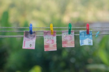 Para aklama konsepti. Rupiah faturaları çamaşır ipine asılı. Para aklamanın sembolü. Uzayın yumuşak odaklanmasını kopyala Para çamaşır ipinde.