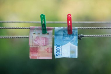 Para aklama konsepti. Rupiah faturaları çamaşır ipine asılı. Para aklamanın sembolü. Uzayın yumuşak odaklanmasını kopyala Para çamaşır ipinde.