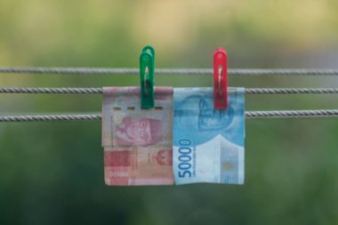 Para aklama konsepti. Rupiah faturaları çamaşır ipine asılı. Para aklamanın sembolü. Uzayın yumuşak odaklanmasını kopyala Para çamaşır ipinde.