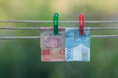 Para aklama konsepti. Rupiah faturaları çamaşır ipine asılı. Para aklamanın sembolü. Uzayın yumuşak odaklanmasını kopyala Para çamaşır ipinde.
