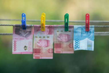 Para aklama konsepti. Rupiah faturaları çamaşır ipine asılı. Para aklamanın sembolü. Uzayın yumuşak odaklanmasını kopyala Para çamaşır ipinde.