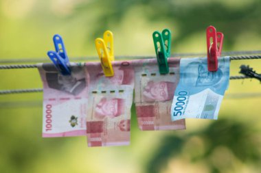 Para aklama konsepti. Rupiah faturaları çamaşır ipine asılı. Para aklamanın sembolü. Uzayın yumuşak odaklanmasını kopyala Para çamaşır ipinde.