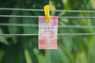 Para aklama konsepti. Rupiah faturaları çamaşır ipine asılı. Para aklamanın sembolü. Uzayın yumuşak odaklanmasını kopyala Para çamaşır ipinde.