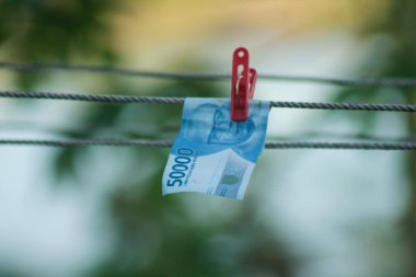 Para aklama konsepti. Rupiah faturaları çamaşır ipine asılı. Para aklamanın sembolü. Uzayın yumuşak odaklanmasını kopyala Para çamaşır ipinde.