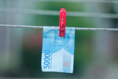 Para aklama konsepti. Rupiah faturaları çamaşır ipine asılı. Para aklamanın sembolü. Uzayın yumuşak odaklanmasını kopyala Para çamaşır ipinde.