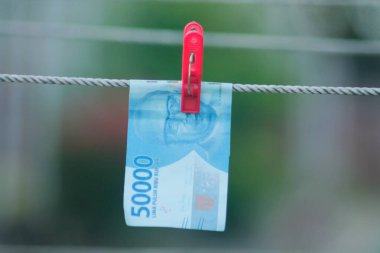 Para aklama konsepti. Rupiah faturaları çamaşır ipine asılı. Para aklamanın sembolü. Uzayın yumuşak odaklanmasını kopyala Para çamaşır ipinde.