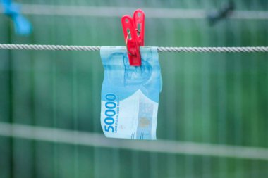 Para aklama konsepti. Rupiah faturaları çamaşır ipine asılı. Para aklamanın sembolü. Uzayın yumuşak odaklanmasını kopyala Para çamaşır ipinde.