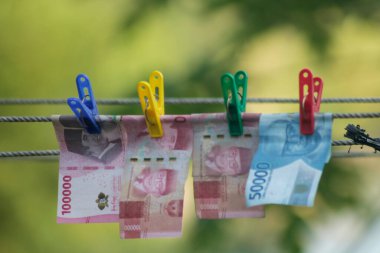 Para aklama konsepti. Rupiah faturaları çamaşır ipine asılı. Para aklamanın sembolü. Uzayın yumuşak odaklanmasını kopyala Para çamaşır ipinde.
