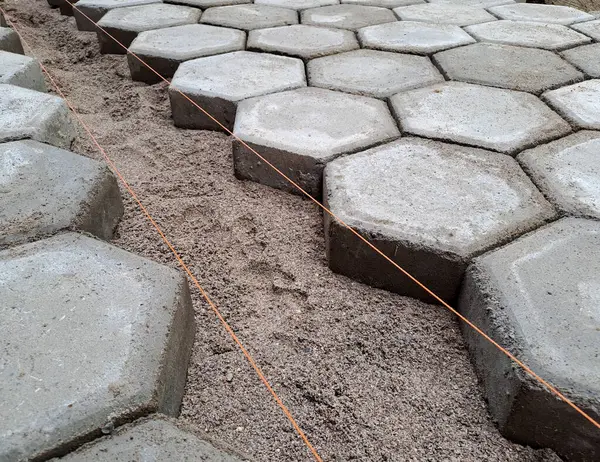 Altıgen kaldırım döşemesi. İnşaat aletleri ve detaylar, plastik çekiçle döşeme. Altıgen asfalt döşeme, kaldırım döşeme