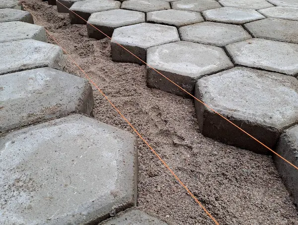 Altıgen kaldırım döşemesi. İnşaat aletleri ve detaylar, plastik çekiçle döşeme. Altıgen asfalt döşeme, kaldırım döşeme