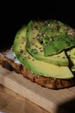 Kepekli tam tahıllı ekmek, üstüne taze avokado dilimleri, susam ve chia tohumları. Omega-3 açısından zengin sağlıklı bir kahvaltı. Bloglar, tarifler, restoranlar ve sağlıklı beslenmeye odaklı markalar için mükemmel..