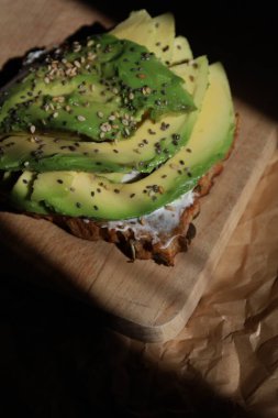 Kepekli tam tahıllı ekmek, üstüne taze avokado dilimleri, susam ve chia tohumları. Omega-3 açısından zengin sağlıklı bir kahvaltı. Bloglar, tarifler, restoranlar ve sağlıklı beslenmeye odaklı markalar için mükemmel..