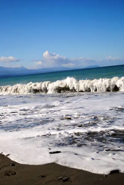 Dalgaları, denizi ve mavi gökyüzü olan güzel sahil.