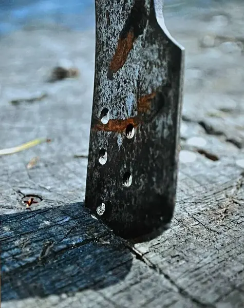 Tahta bir yüzeye saplı bir bıçağın yakın çekim görüntüsü.