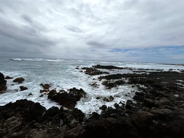 Bulutlu gökyüzünün altında kayaların dikey görüntüsü