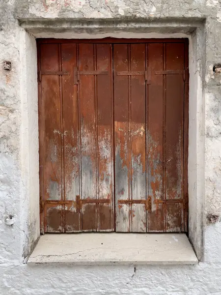 Yıpranmış kırmızı ahşap bir pencereye yakın plan, kabuk soyma boya, kırsal cazibe ve tasarım ve arka planda kullanılması için tarihi karakter sunuyor