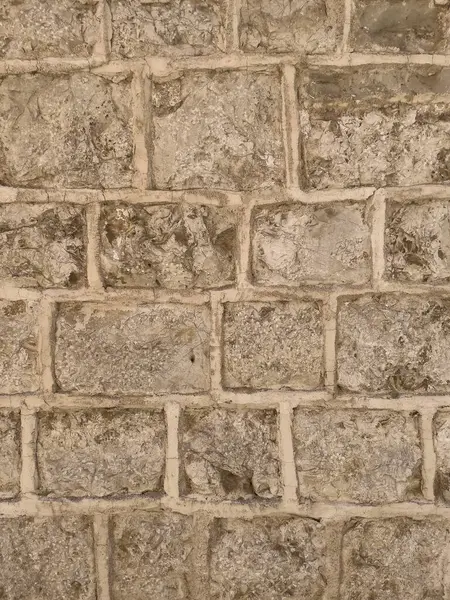 Düz olmayan tuğla yüzeyi ve harç çizgileri olan desenli duvar..