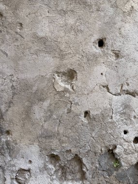 Görünür çatlaklar, delikler ve desenli sıva içeren kabataslak bir bej duvarı kapat. Grunge veya klasik tasarım arka planlarında kullanmak için ideal.