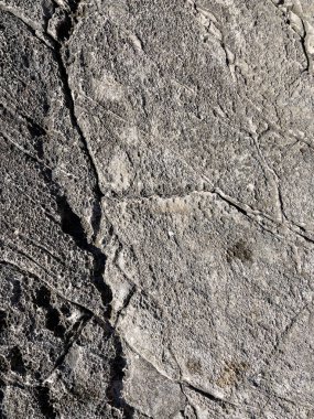 Koyu gözenekli kaya yüzeyini çatlaklar ve pürüzlü dokuyla kapatın, arka plan veya tasarım elementleri için idealdir.