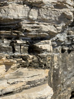 Katmanlı kaya kaya dokusu. Görünür tortu çizgileri ve renk değişimleriyle kaplı katmanlı kaya uçurumlarına yakın çekim, jeolojik arka planlar için ideal. Yüksek kalite fotoğraf
